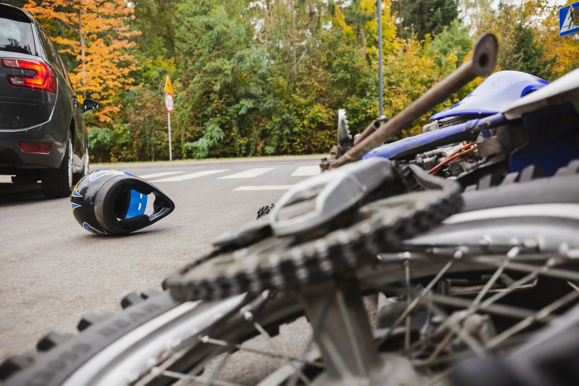 Motorcycle and car accident at a crosswalk with helmet on the ground.