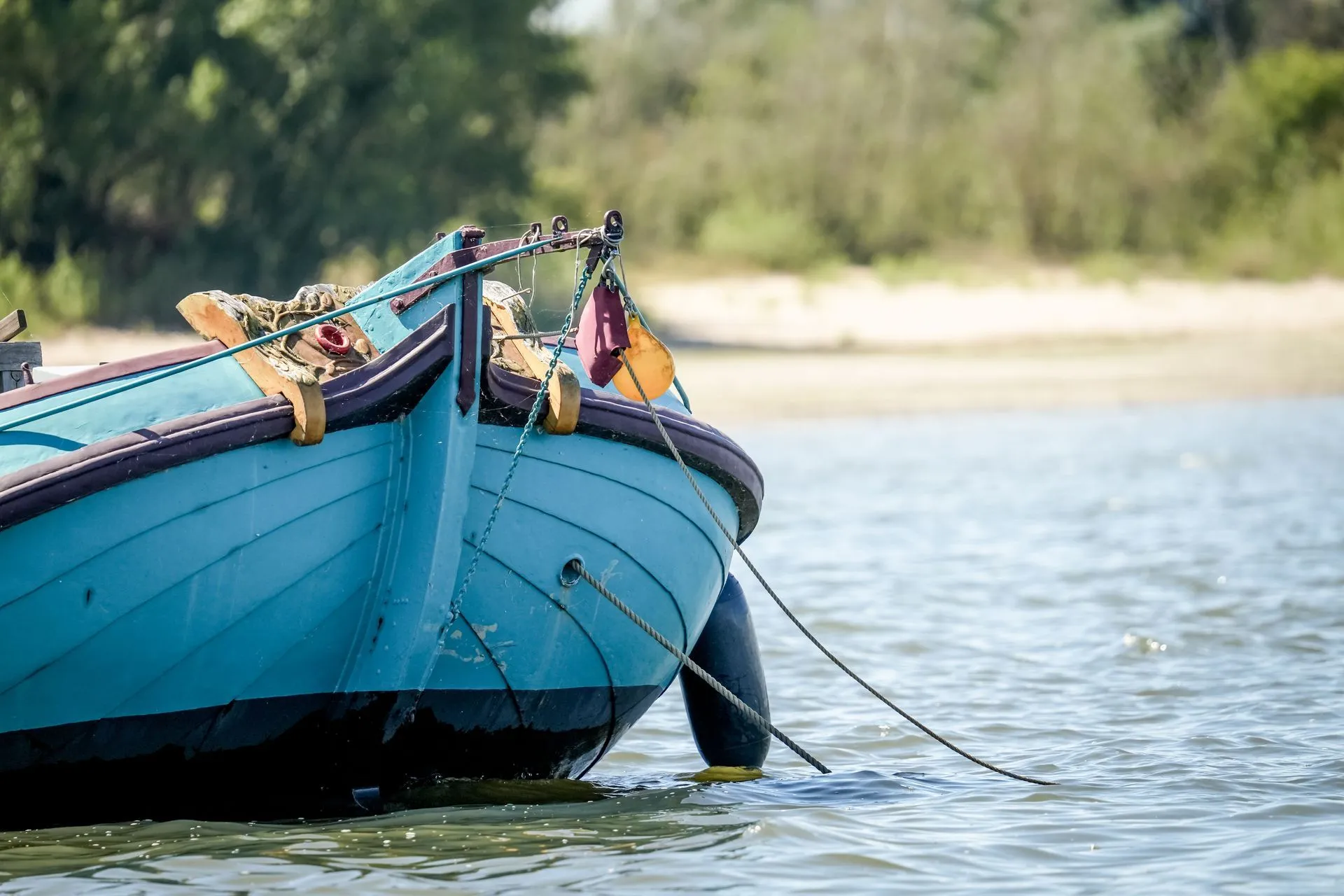 Blue rowboat in water near sandy shore.