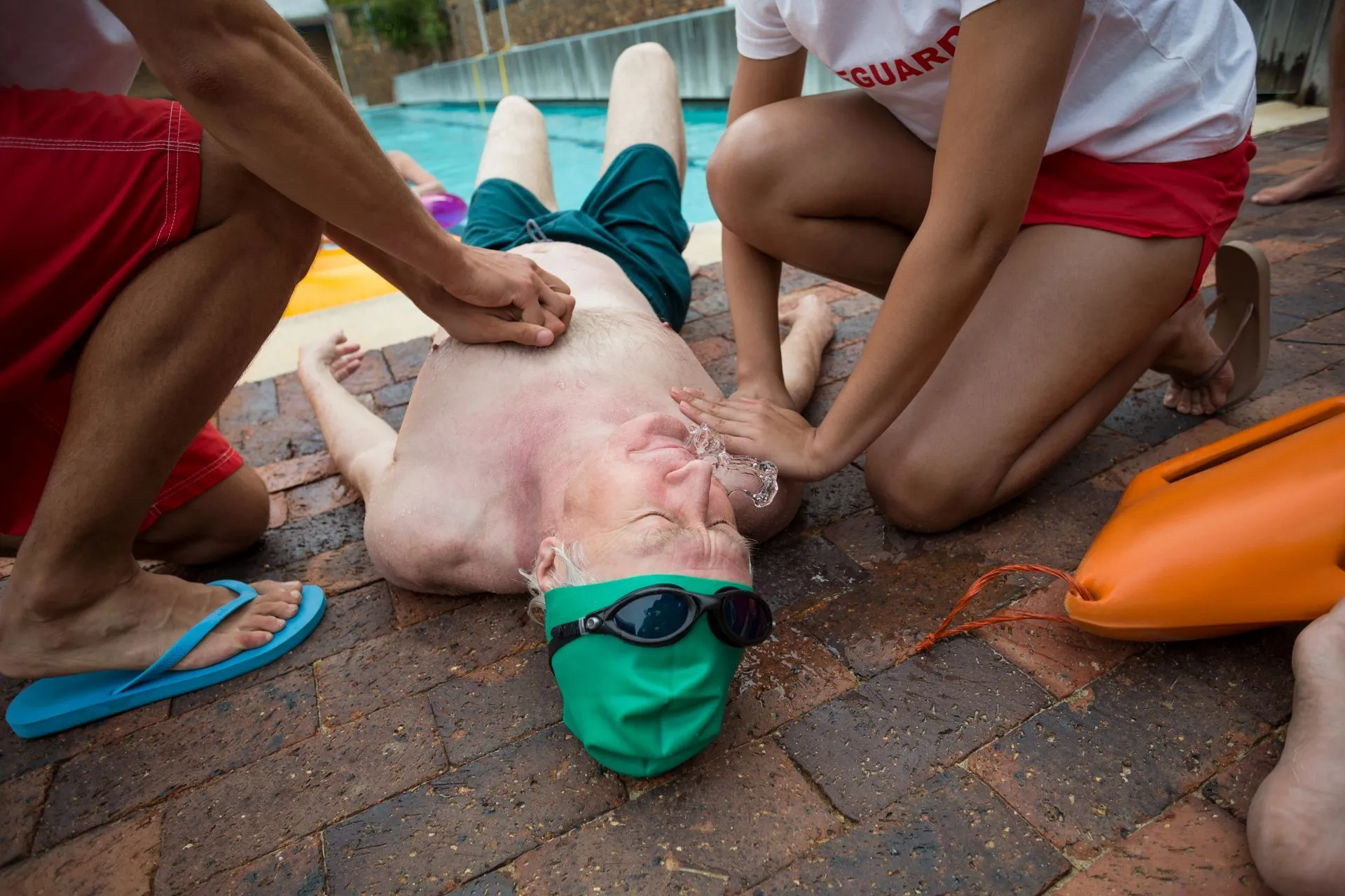 Lifeguards performing CPR on a person at a pool.